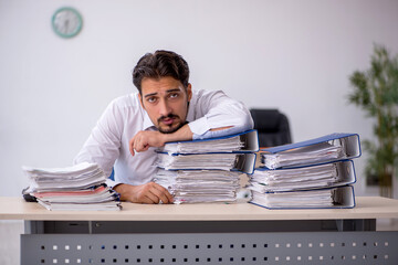 Young male employee and too much work in the office