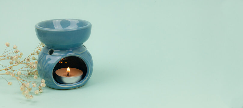 Essential oil in an aroma lamp on a blue background, banner, copy space