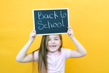 schoolgirl holding a tablet in her hands with the inscription Back to school on a yellow background.