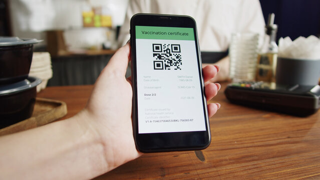 QR code, covid vaccination passport control close-up. Scanning coronavirus electronic medical certificate on smartphone in cafe or restaurant, green zone. - Powered by Adobe