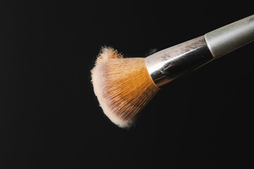 Fototapeta premium Makeup brush shaking off powder on black background