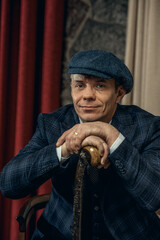 A man posing in the image of an English retro gangster of the 1920s dressed in a suit and flat cap...