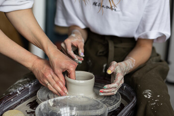 Fototapeta na wymiar Two young women doing handmade pottery on the potter's wheel. Artist at work