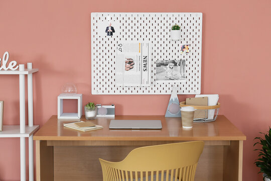 Modern workplace with peg board on pink wall