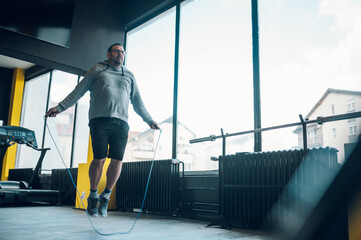 Middle aged man training in the gym with jump rope