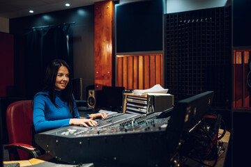 Woman music producer working on a mixing soundboard in a studio.