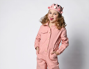 playful girl in a cotton pink summer jumpsuit and a plush short, looks at you slyly and shows her tongue.
