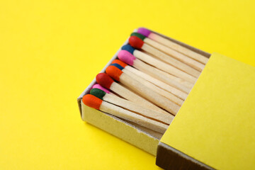 Fototapeta premium Box with different new matchsticks on yellow background, closeup