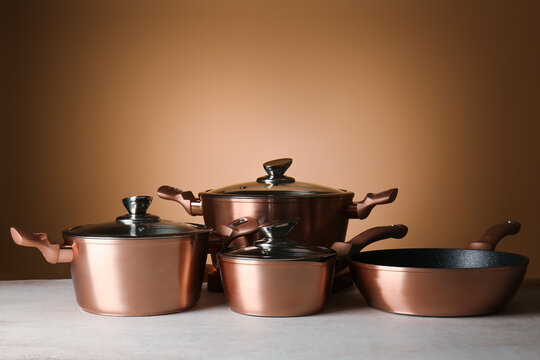 Set of copper utensils on table against color background