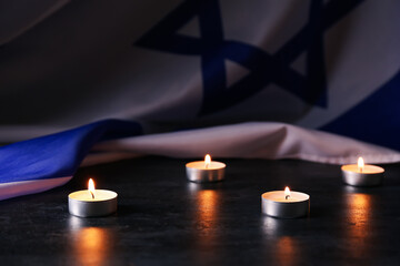 Burning candles and flag of Israel on dark background. Holocaust remembrance day