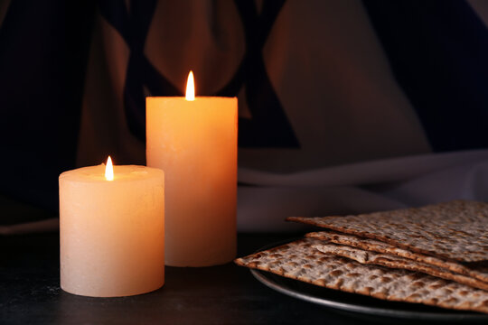 Burning candles and matza on dark background. Holocaust remembrance day