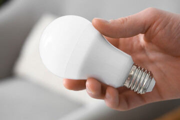 Man holding light bulb at home, closeup