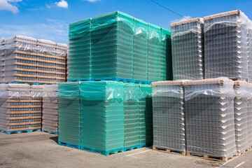 The open air storage and carriage of the finished product at industrial facility. A glass clear bottles for alcoholic or soft drinks beverages and canning jars stacked on pallets for forklift.
