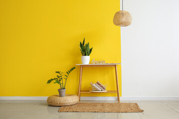 Pouf, table with houseplants and books near color wall