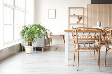 Interior of light dining room with table, sofa and shelving unit