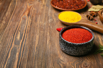 Bowl of red chili powder on wooden background, closeup