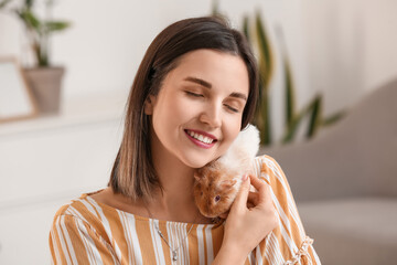 Beautiful young woman with cute guinea pig at home
