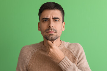 Obraz premium Ill young man with sore throat on green background