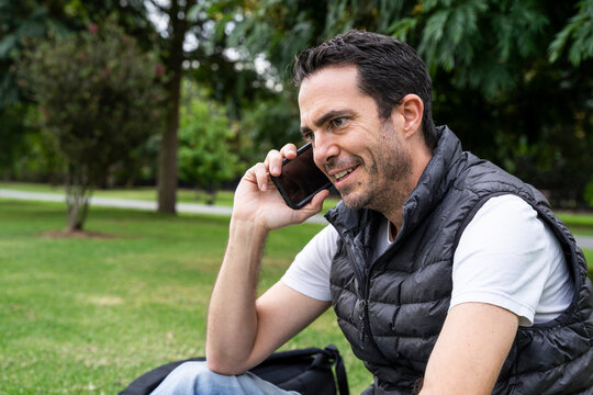 White Hispanic Man Using Phone At Park. Middle Aged Man Talking By Phone Outdoors.