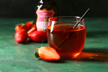 Glass of fresh strawberry kombucha on green background, closeup