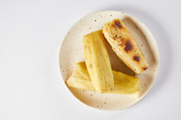 Humitas are savory steamed fresh corn cakes, a traditional Ecuadorian appetizer. On a white background. 