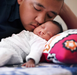 Under the loving gaze of his father. Shot of a young father bonding with his baby girl who has a...