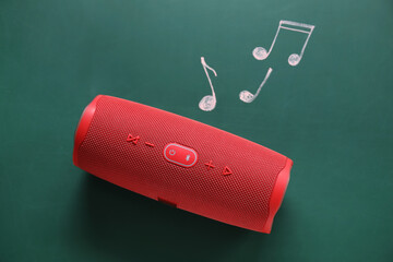 Wireless portable speaker and drawing of music notes on green background