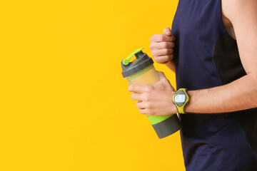 Sporty man with fitness tracker and bottle of water on color background, closeup