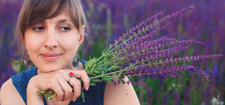 Natural beauty - Young woman with flowers bouquet in wildflowers garden