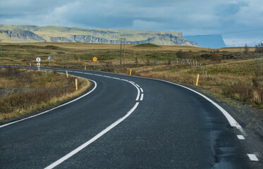 Highway road and mountain view during auto trip in Iceland. Spectacular Icelandic landscape with  scenic nature: fjords, fields, clouds, glaciers, waterfalls.