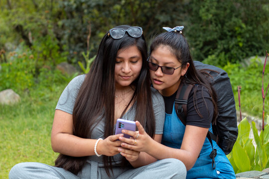 Retrato de dos hermosas chicas tomándose fotos en aire libre,
Amigas felices revisando teléfono inteligente en aire libre,Dos chicas usando el móvil en medio de un camino rodeado de montañas