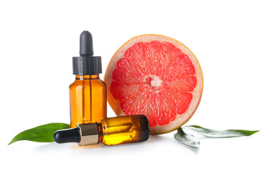 Bottles with essential oil and half of grapefruit on white background