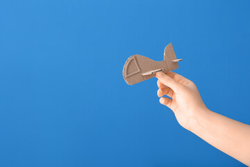Female hand with cardboard plane on color background