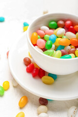 Cup with different jelly beans on light background, closeup
