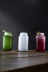 Bebidas de yerbabuena, coco y frutos rojos sobre una mesa de madera con un fondo gris