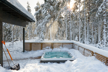 The warm hot tub invites you to relax in the beautiful winter landscape as the snow slowly falls down. - Powered by Adobe