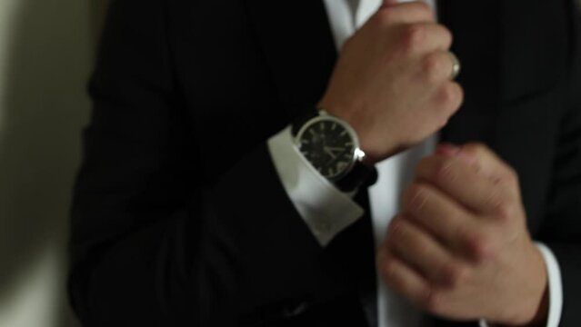 a man in a suit adjusts his watch on his hand