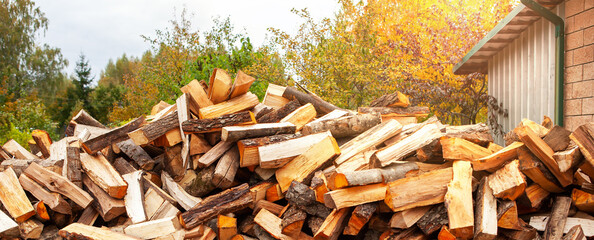 Stock of firewood for heating the house. The trees were cut down and split into firewood to be used as heating fuel in fireplaces and stoves, firewood background.