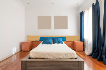 Bedroom with king size bed with cherry wood floors and blue curtains with white curtains