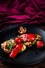 grilled vegetables and mushrooms are served on a black plate