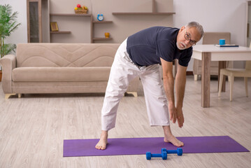 Old man doing sport exercises at home