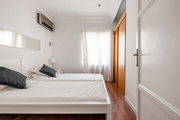 Bedroom with two white single beds, cherry wood sliding door wardrobe and matching floors