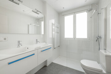 New bathroom with white porcelain double sink and rectangular frameless mirror, radiator for drying towels inside the shower and white aluminum window