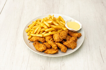 Menu plate with battered chicken strips, French fries and sauce for dipping