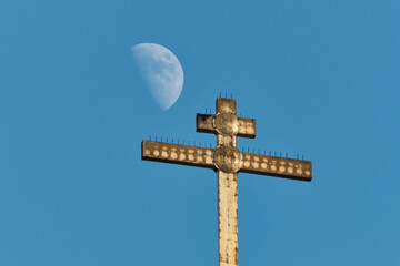Orthodox cross and waxing gibbous moon in daylight. Russia. Moscow