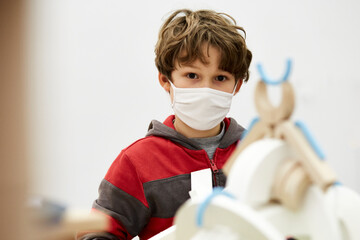 enfant garçon avec masque fait des constructions