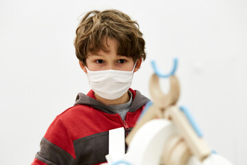 enfant garçon avec masque fait des constructions