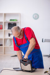 Old repairman repairing sandwich maker at workshop