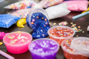 Young kids playing with colorful slime kit with glitter, toys, texture craft balls, and sparkles