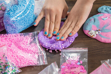 Young kids playing with colorful slime kit with glitter, toys, texture craft balls, and sparkles